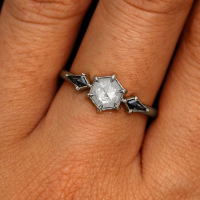 A model's hand wearing a 950 platinum Hexagon Salt and Pepper Diamond Black and White Ring