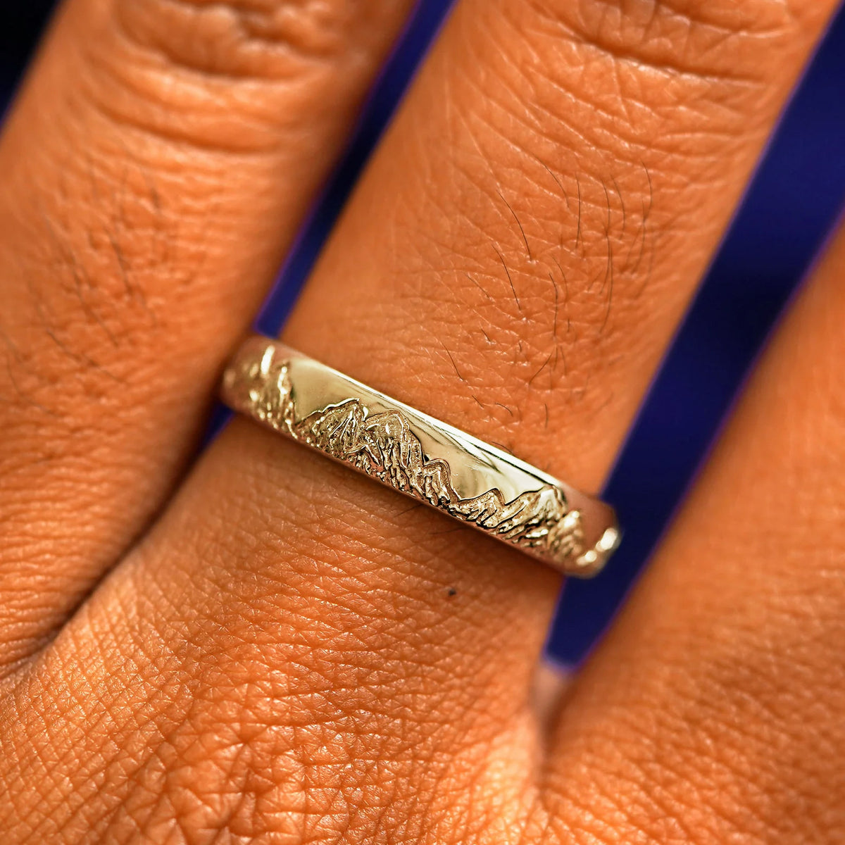 Close up view of a model's fingers wearing a 14k champagne gold Mountains Band