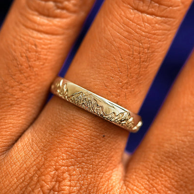 Close up view of a model's fingers wearing a 14k champagne gold Mountains Band