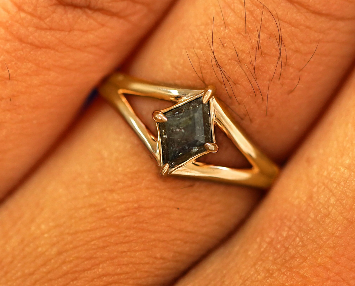 Close up view of a model's fingers wearing a yellow gold salt and pepper diamond Gemstone Kite Ring
