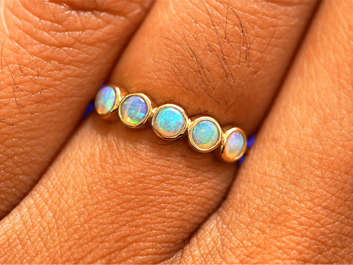 Close up view of a model's hand wearing a 5 Gemstone Ring in opal