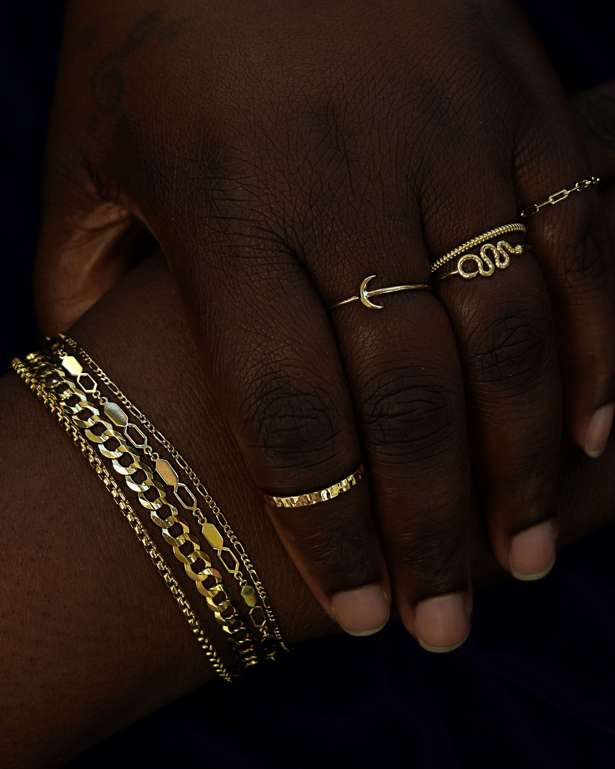 A models with their hands posed one of the other wearing Automic Gold rings and chain bracelets in yellow gold
