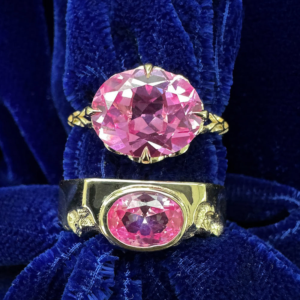 Two custom engagement rings with similar pink sapphire oval stones in two different style bands