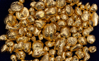 A bunch of solid gold nuggets on a dark blue background