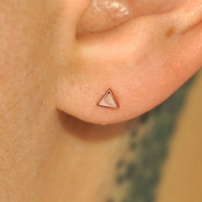 Close up view of a model's ear wearing a 14k rose gold Triangle Earring