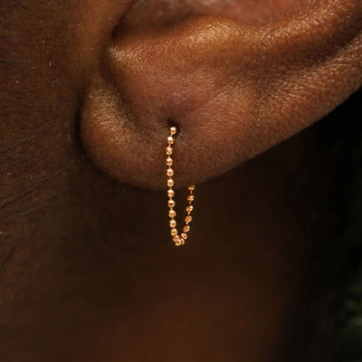 Close up view of a model's wearing a 14k rose gold Chain Loop Earring