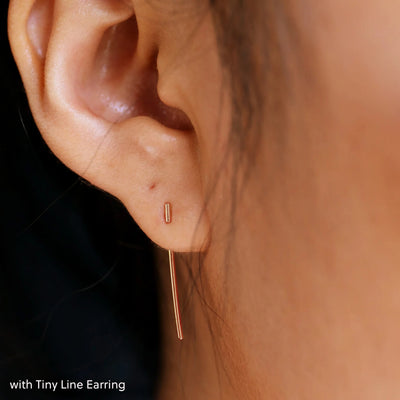 Close up view of a model's ear wearing a rose gold Line Jacket with a Tiny Line Earring