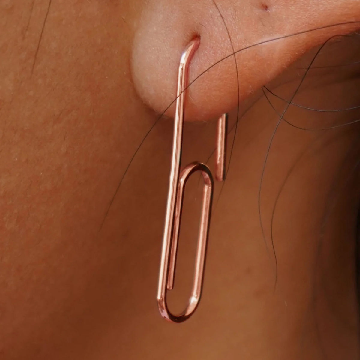Close up view of a model's ear wearing a rose gold Not A Paper Clip Earring