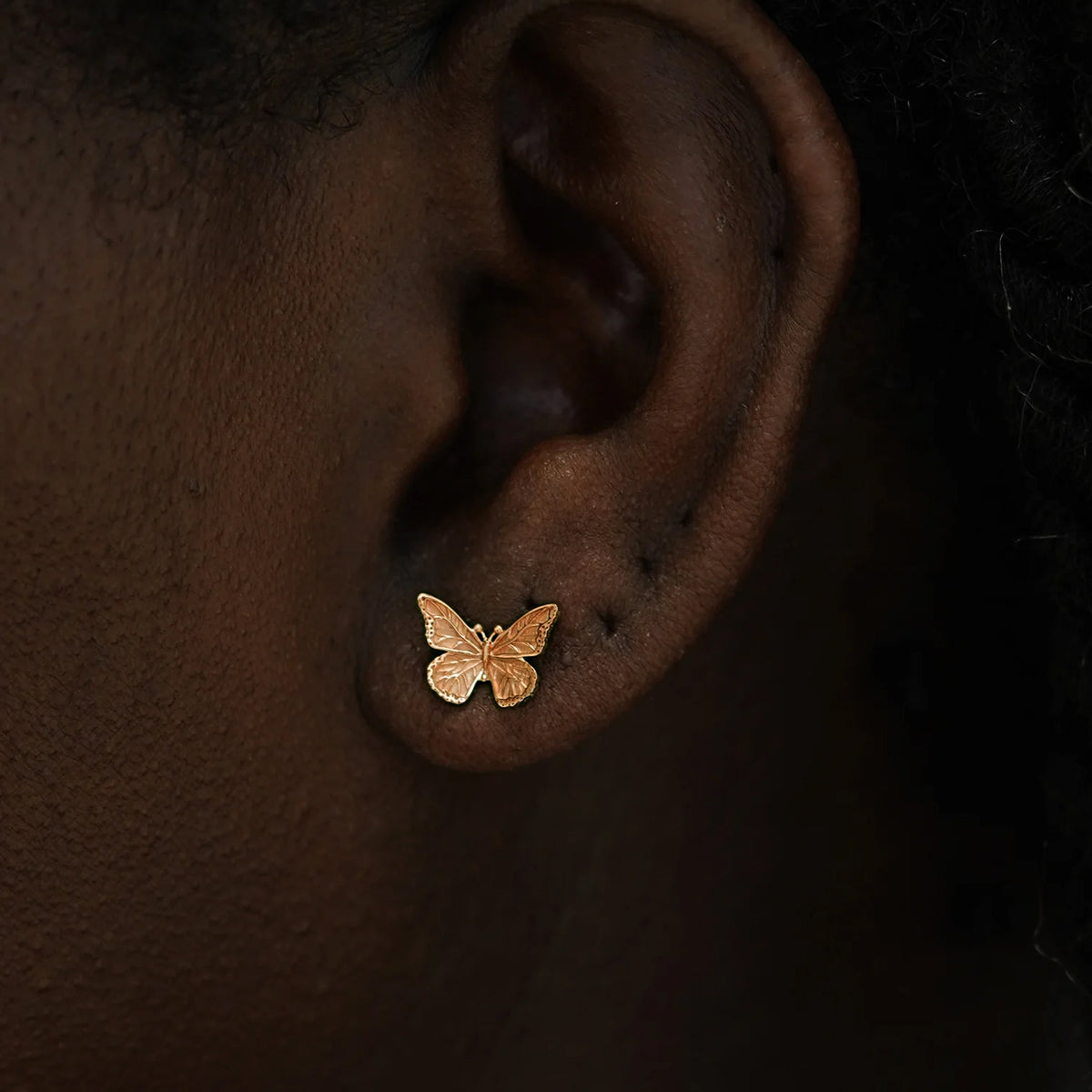 Close up view of a model's ear wearing a 14k rose gold Butterfly Earring