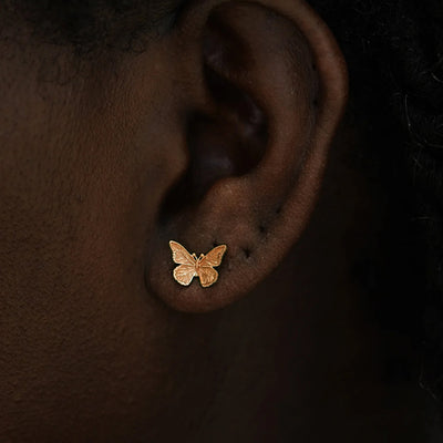 Close up view of a model's ear wearing a 14k rose gold Butterfly Earring