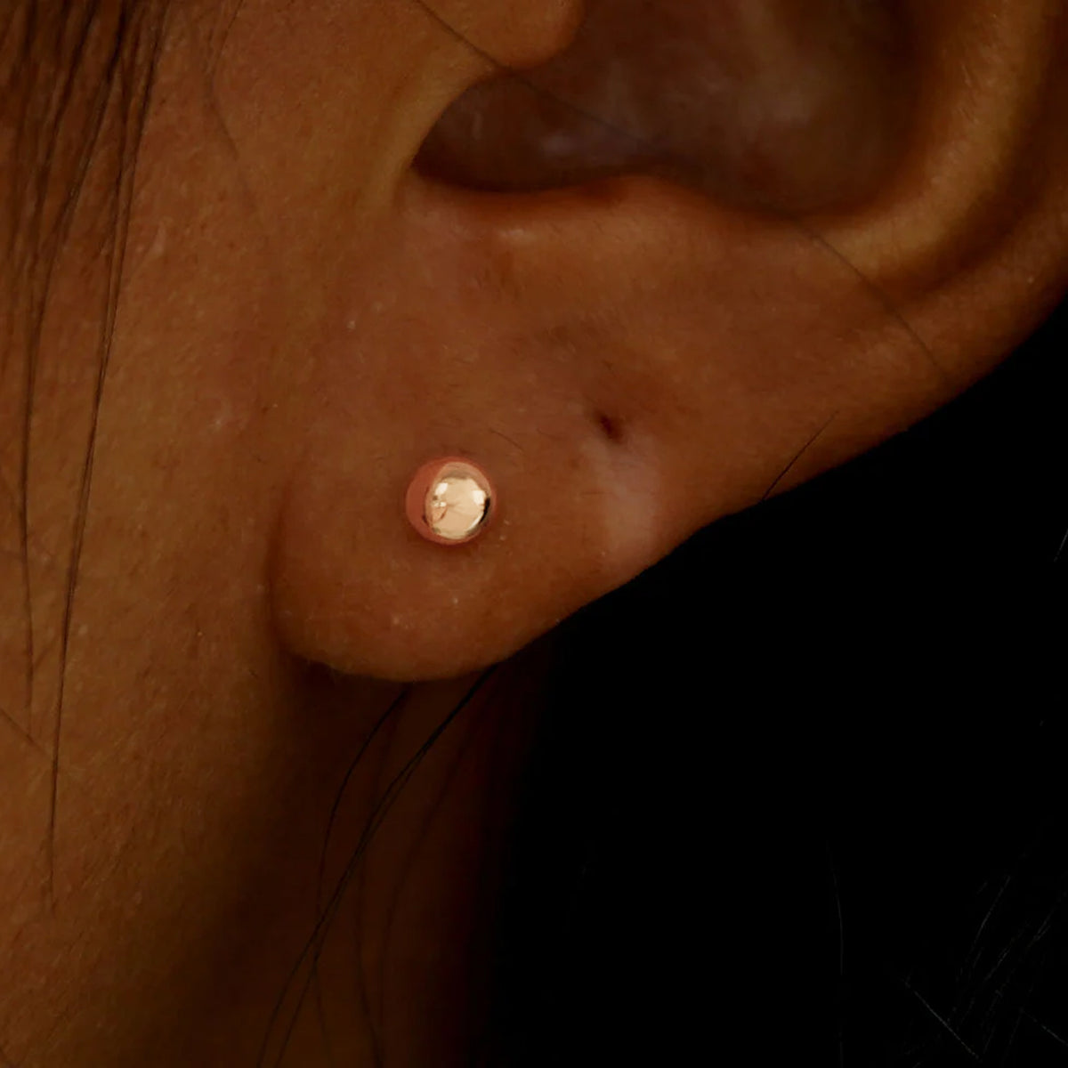 A model's ear wearing a solid rose gold Medium Ball Earring