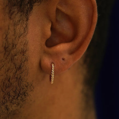 Close up view of a model's ear wearing a rose gold Medium Rope Huggie Hoop