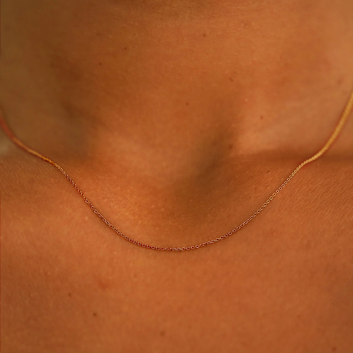 14k rose gold Gold cable chain  necklace on a person's neck with a close-up focus on the jewelry.