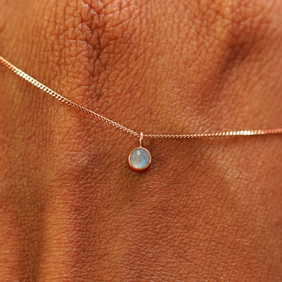 Close up view of a 14k rose gold Labradorite Necklace draped across the back of a model's hand