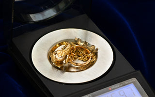 Various gold jewelry items on a scale being weighed