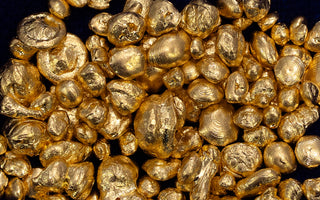A bunch of solid gold nuggets on a dark blue background