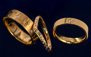 Three celestial themed wedding bands all in yellow gold and diamonds on a dark blue background