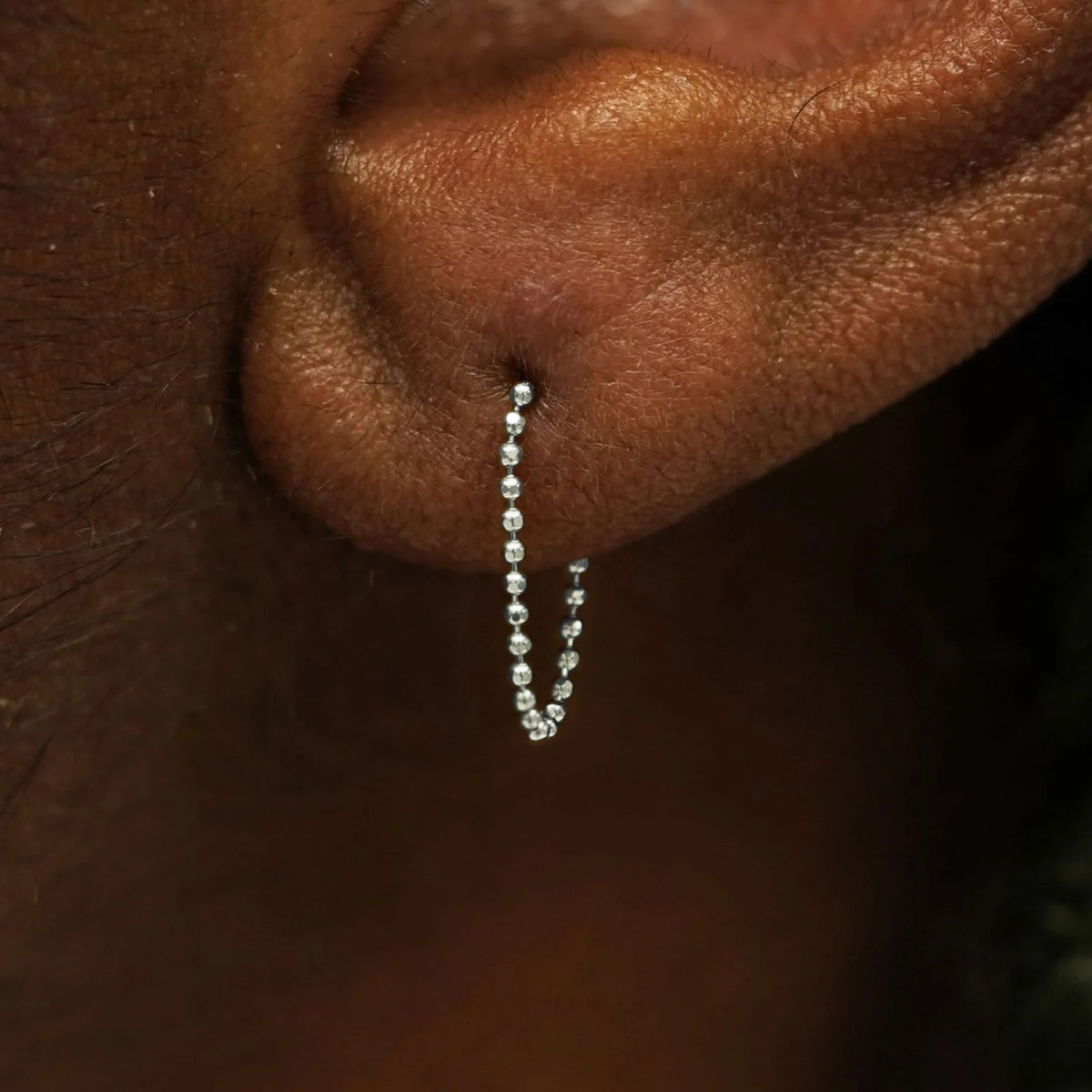 Close up view of a model's wearing a 14k white gold Chain Loop Earring