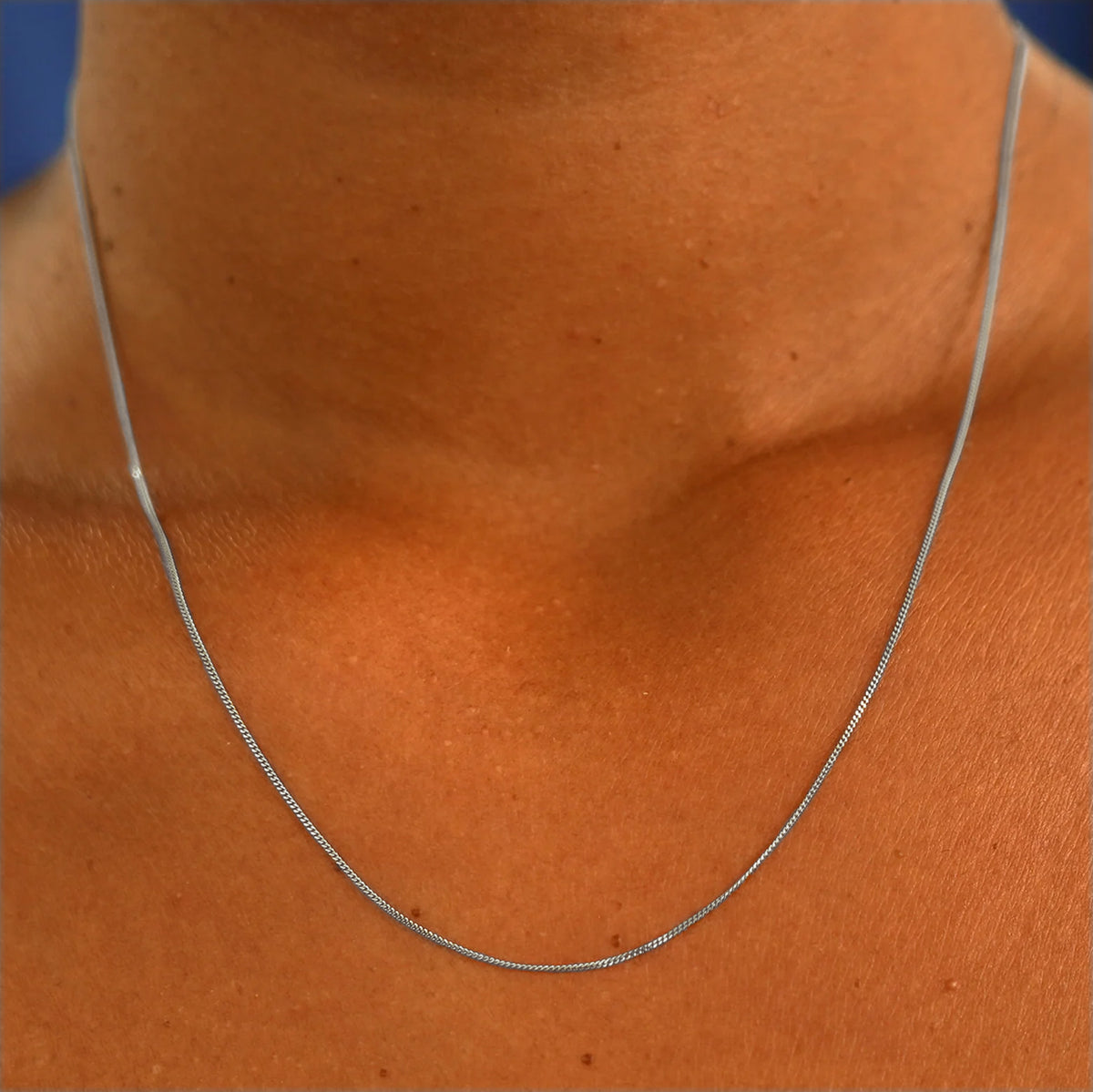 Close up view of a model's neck wearing a solid 14k white gold Essential Chain