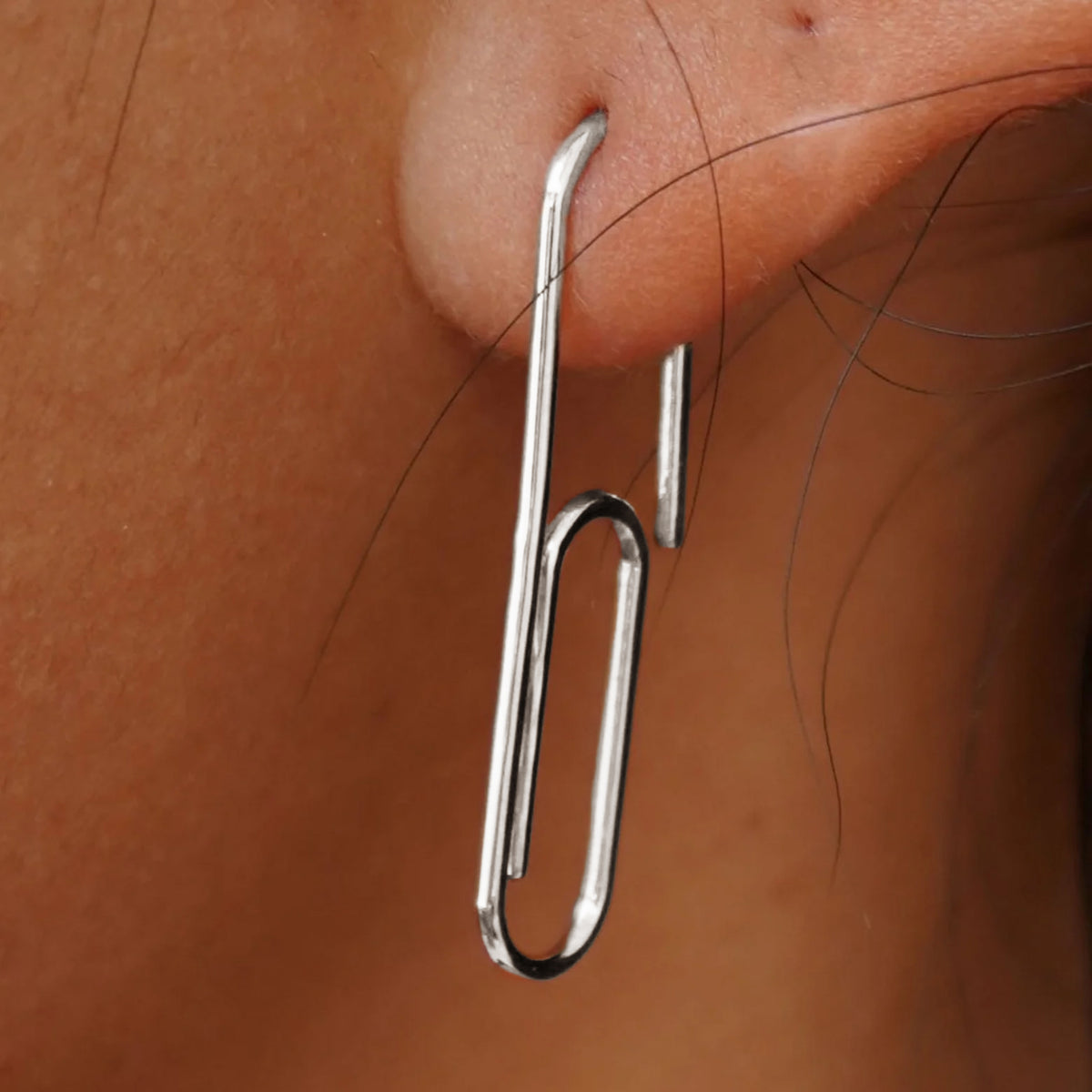 Close up view of a model's ear wearing a white gold Not A Paper Clip Earring