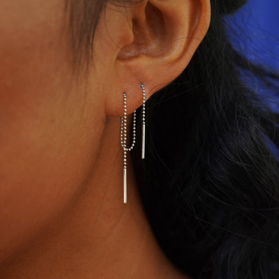 Close up view of a model's ear wearing a white gold Threader through two piercings to create a loop behind their ear