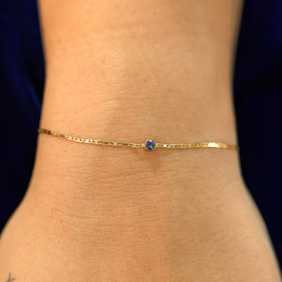 A model's wrist wearing a solid 14k yellow gold Alexandrite Bracelet