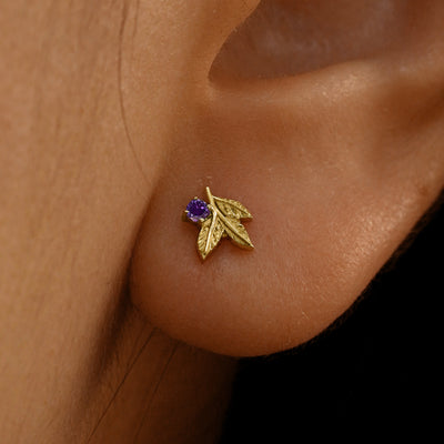 Close up view of a model's ear wearing a 14k yellow gold amethyst 3 Leaves Gemstone Earring