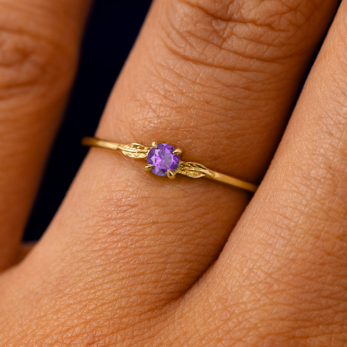 A solid 14k yellow gold Amethyst Gemstone Two Leaf Ring on a model's finger