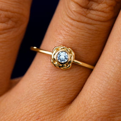 A solid 14k yellow gold Aquamarine Gemstone Flower Ring on a model's finger