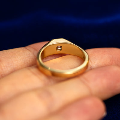 A asscher moissanite signet ring laying flat in a models hand to show the thickness of  the band