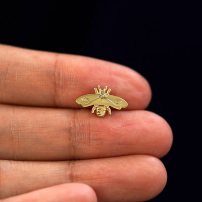 A yellow gold Bee Earring laying facedown on a model's fingers to show the underside view