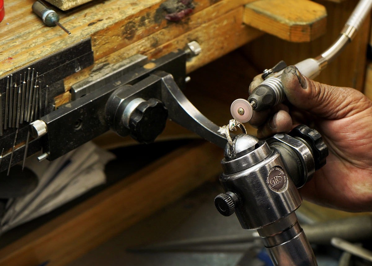 An Automic Gold jeweler polishing a gemstone ouroboros ring