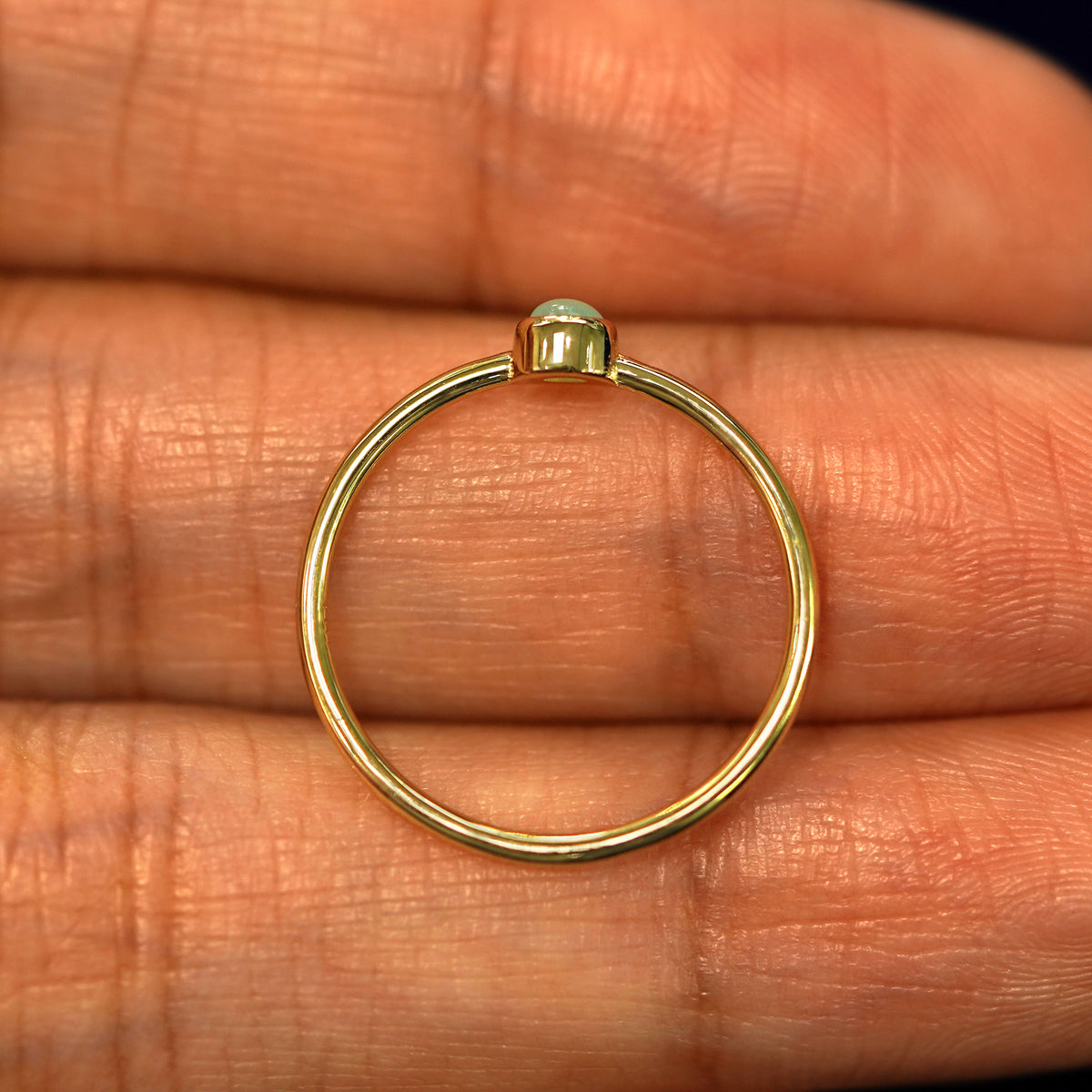 A yellow gold Jade Ring in a model's hand showing the thickness of the band