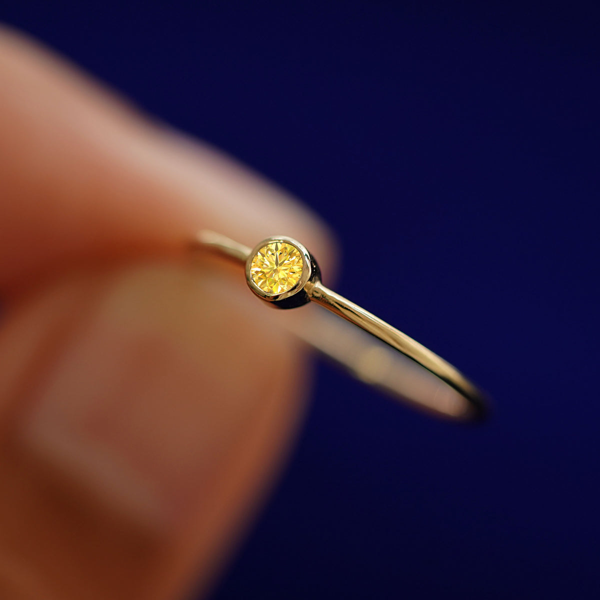 A model holding a Yellow Diamond Ring tilted to show the details of the bezel setting