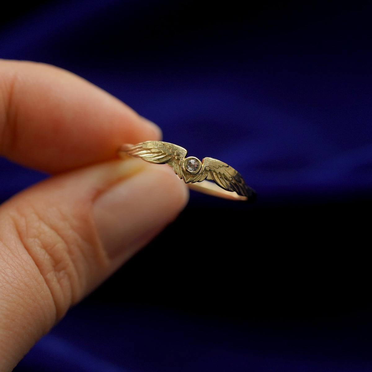 A model holding a 14k gold salt and pepper Diamond Wings Ring between two fingers to show details 
