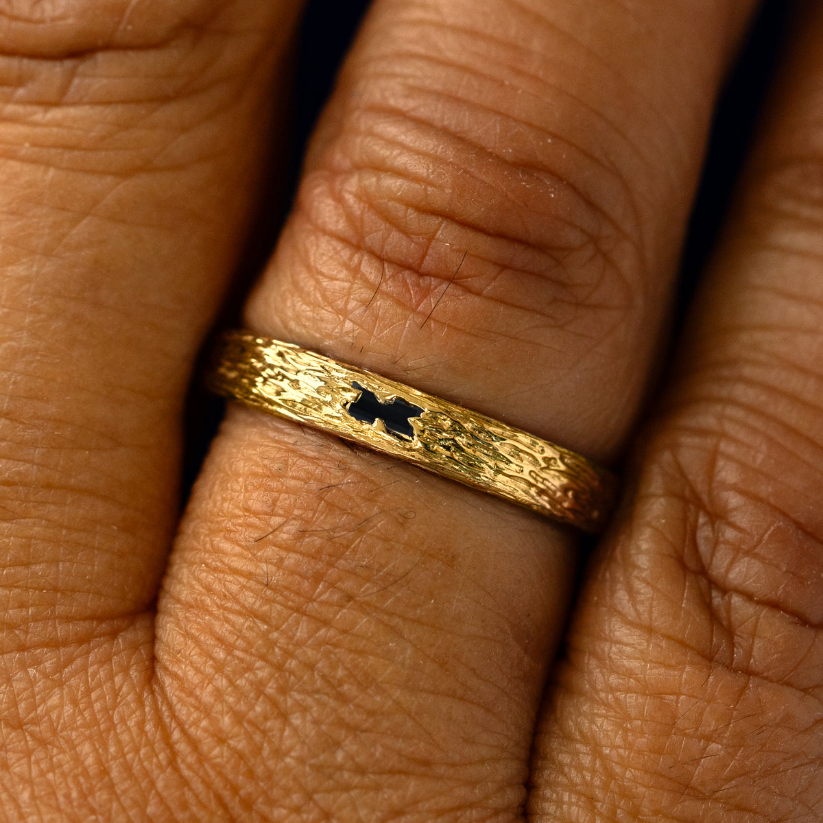 A black baguette diamond raw band on a models finger