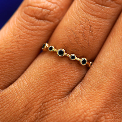 Close up view of a model's fingers wearing a 14k yellow gold Infinity Black Diamond Ring