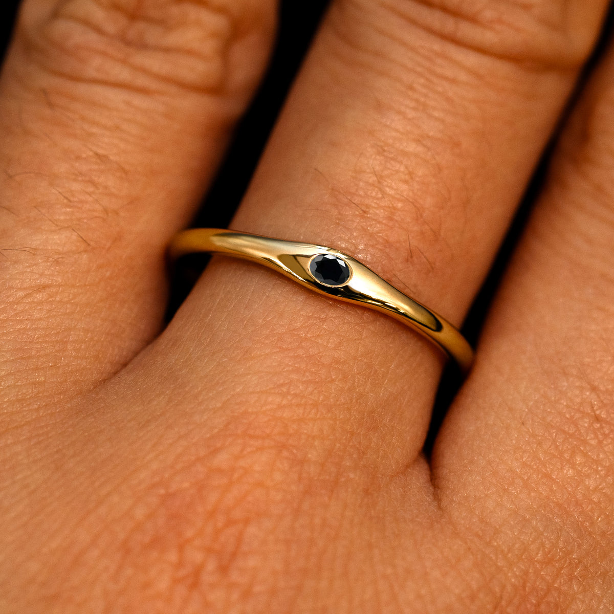 A 14k yellow gold Flush Set Oval Black Diamond Ring on a model's finger