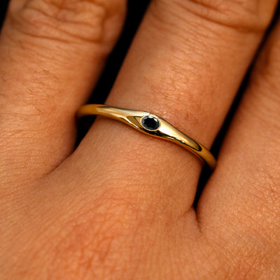 A 14k yellow gold Flush Set Oval Black Diamond Ring on a model's finger