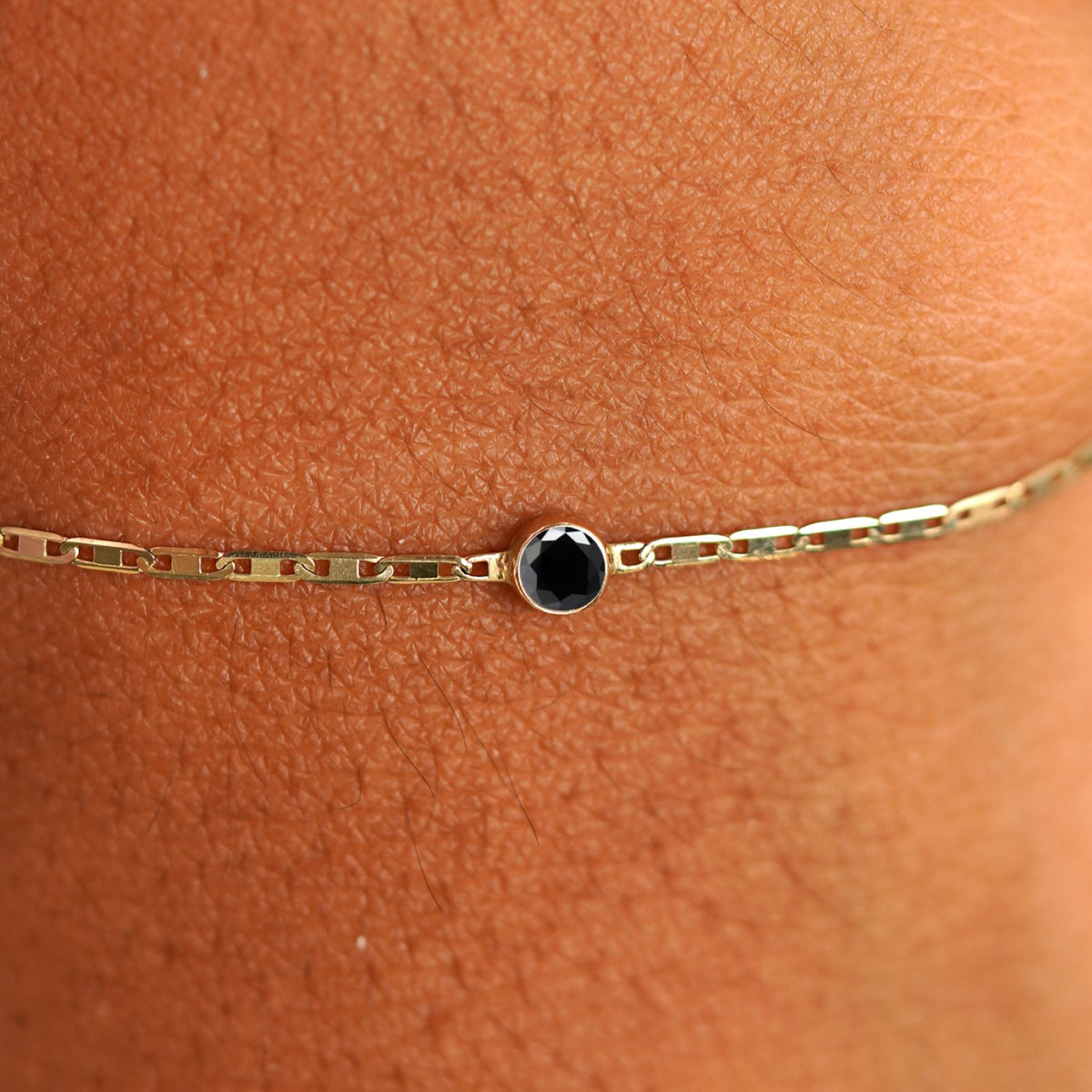 Close up view of a models wrist wearing 14k yellow gold Black Diamond Bracelet