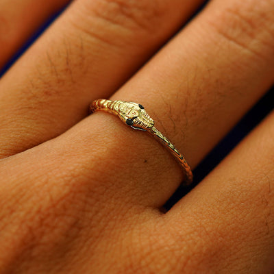 Close up view of a model's hand wearing a yellow gold black diamond Gemstone Ouroboros Snake Ring