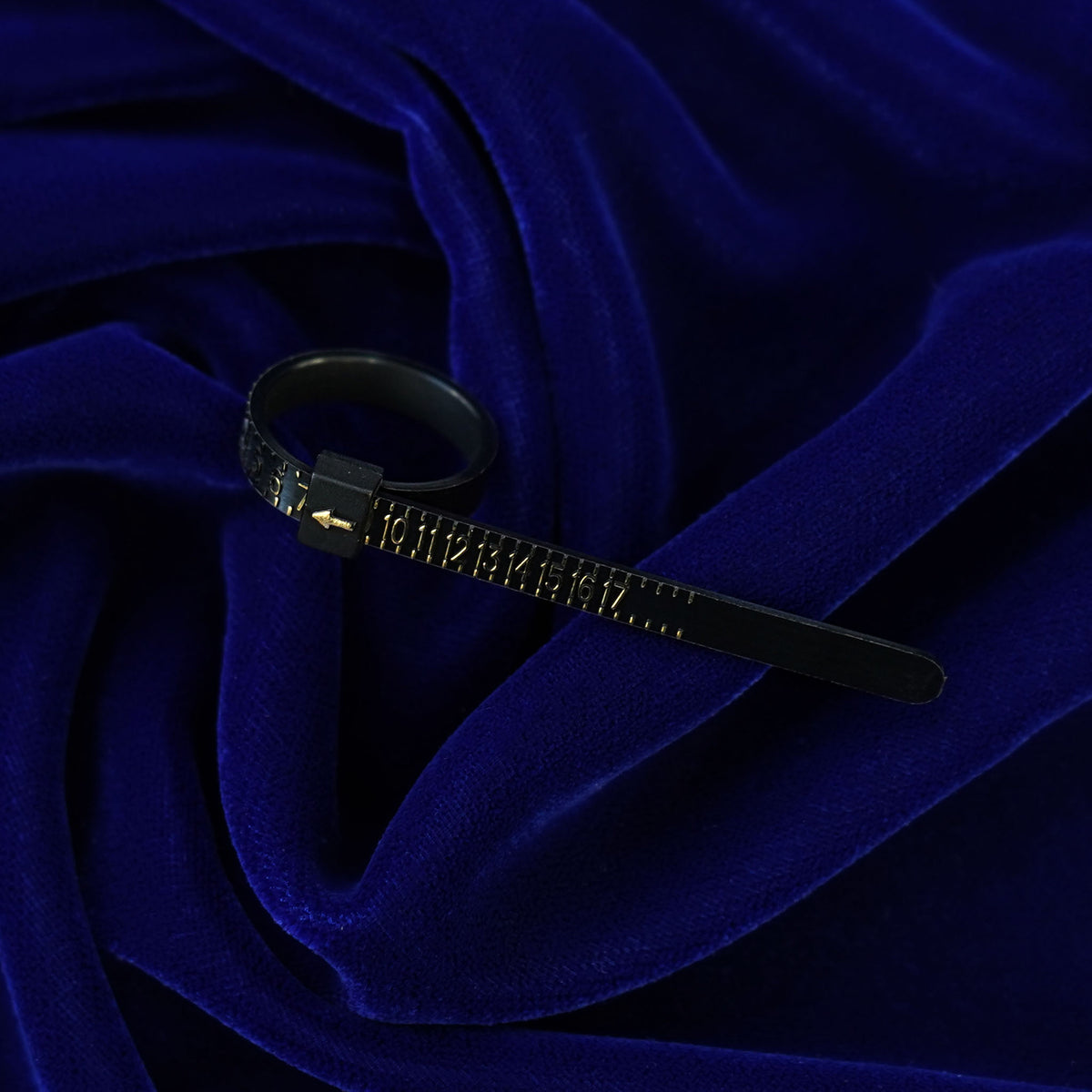 A black Ring Sizer with gold lettering indicating ring size 7 sitting on a dark blue background