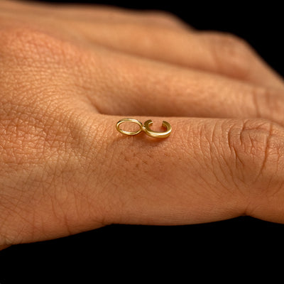 A solid 14k gold Block Initial Charm for chain in the letter C laying on the back of a model's finger