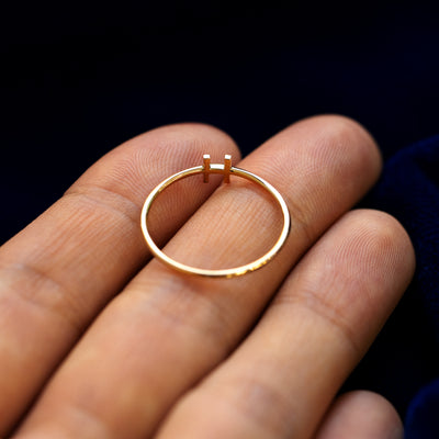 A yellow gold block initial letter H ring in a model's hand showing the underside of the letter