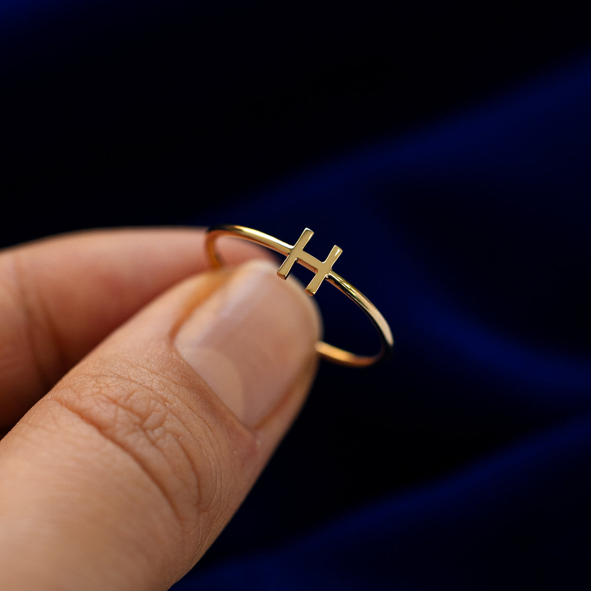 A model holding an block initial letter H ring tilted to show details
