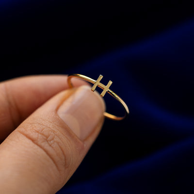 A model holding an block initial letter H ring tilted to show details