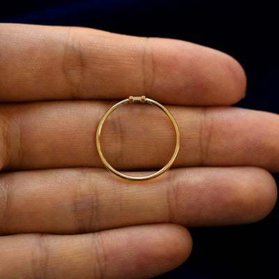 A yellow gold block initial letter H ring in a model's hand showing the thickness of the band
