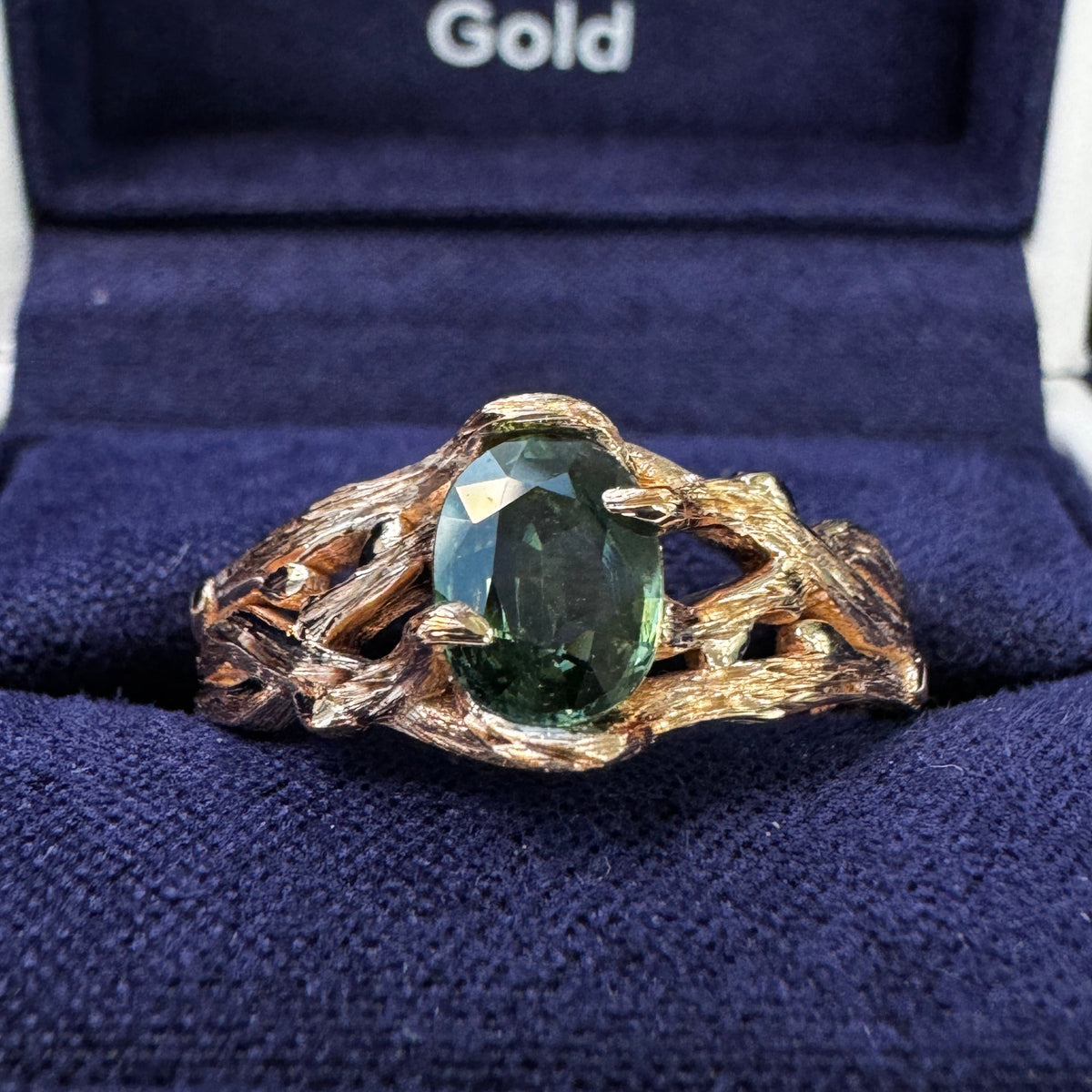 A photo of 14k Rose Gold Branch-prongs-set ~7x5.5mm Oval Dark Green Sapphire on Tapered Tree-inspired Band Custom Ring