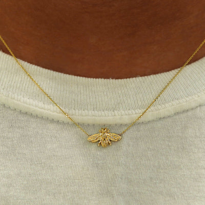 Close up view of a model's neck wearing a yellow gold Bee Necklace