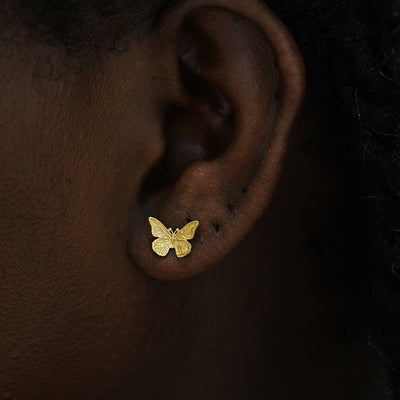 Close up view of a model's ear wearing a 14k gold Butterfly Earring